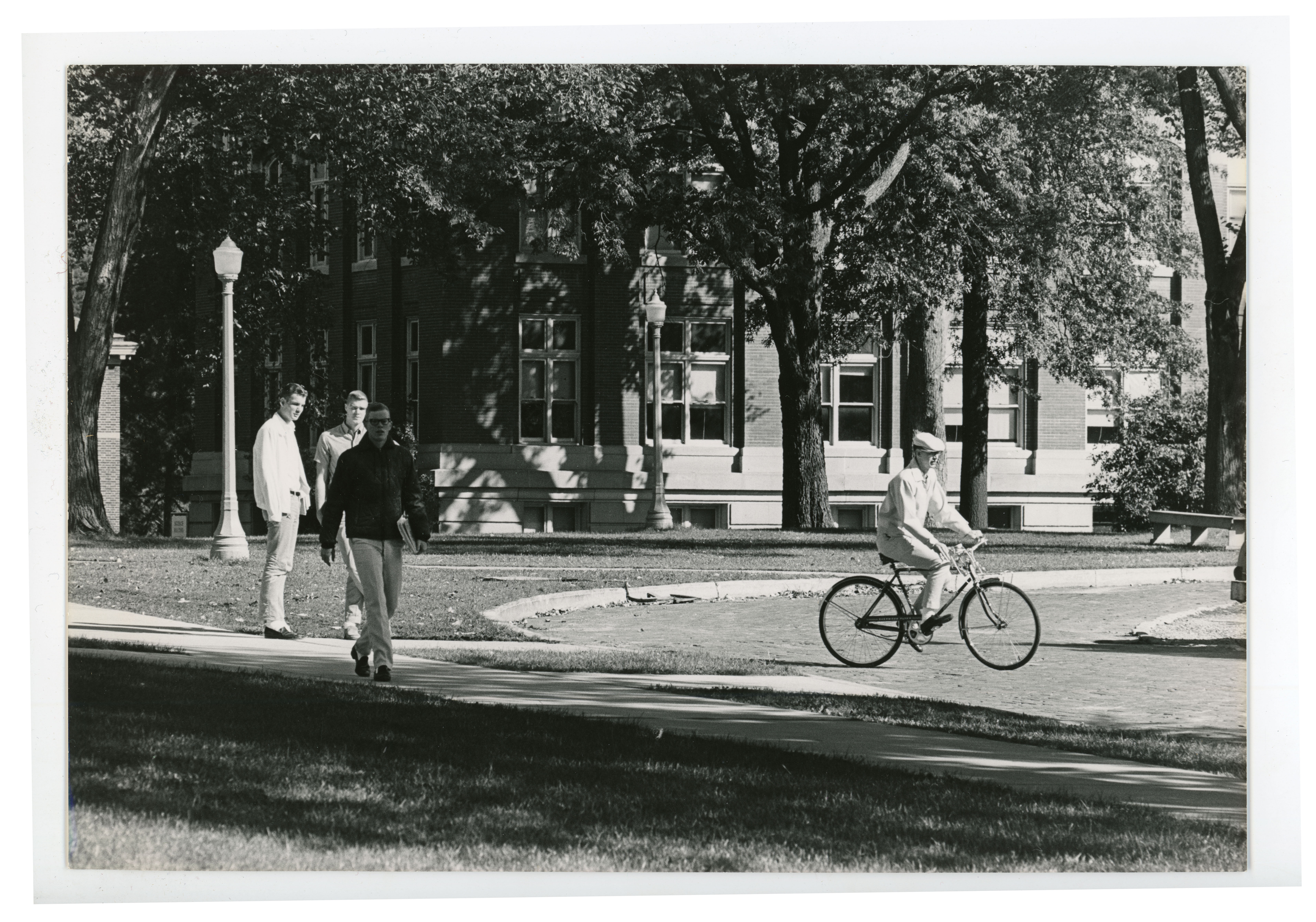 Cyclist and three walkers passing Begeman Hall