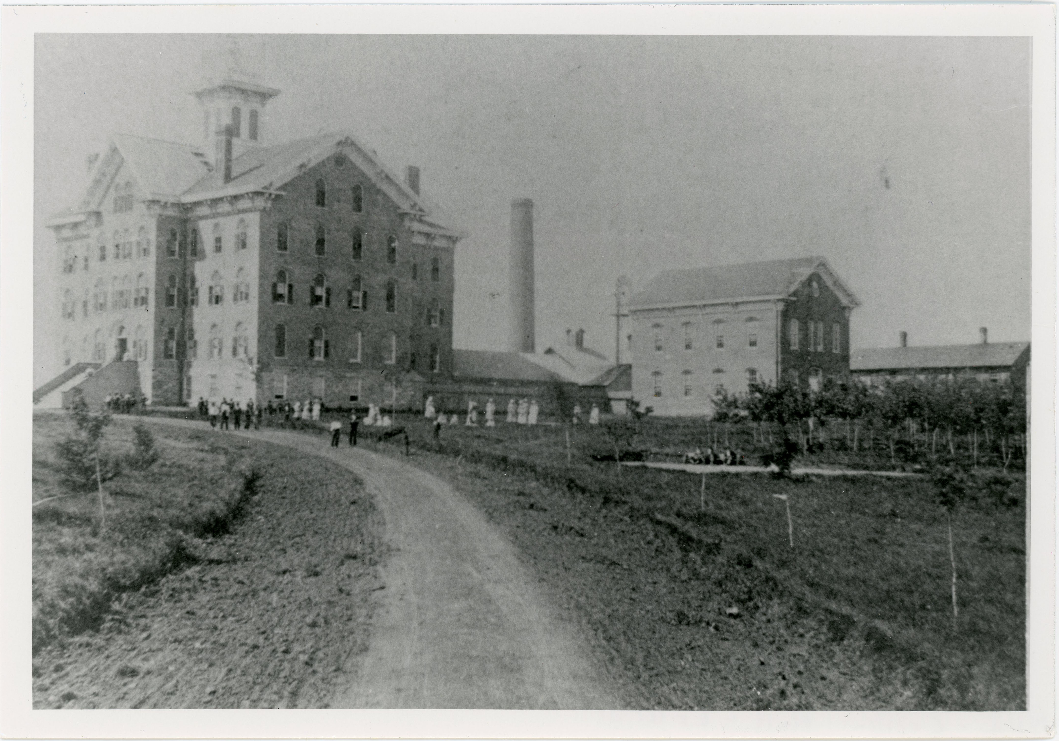 People on lawn between building with cupola and smaller building