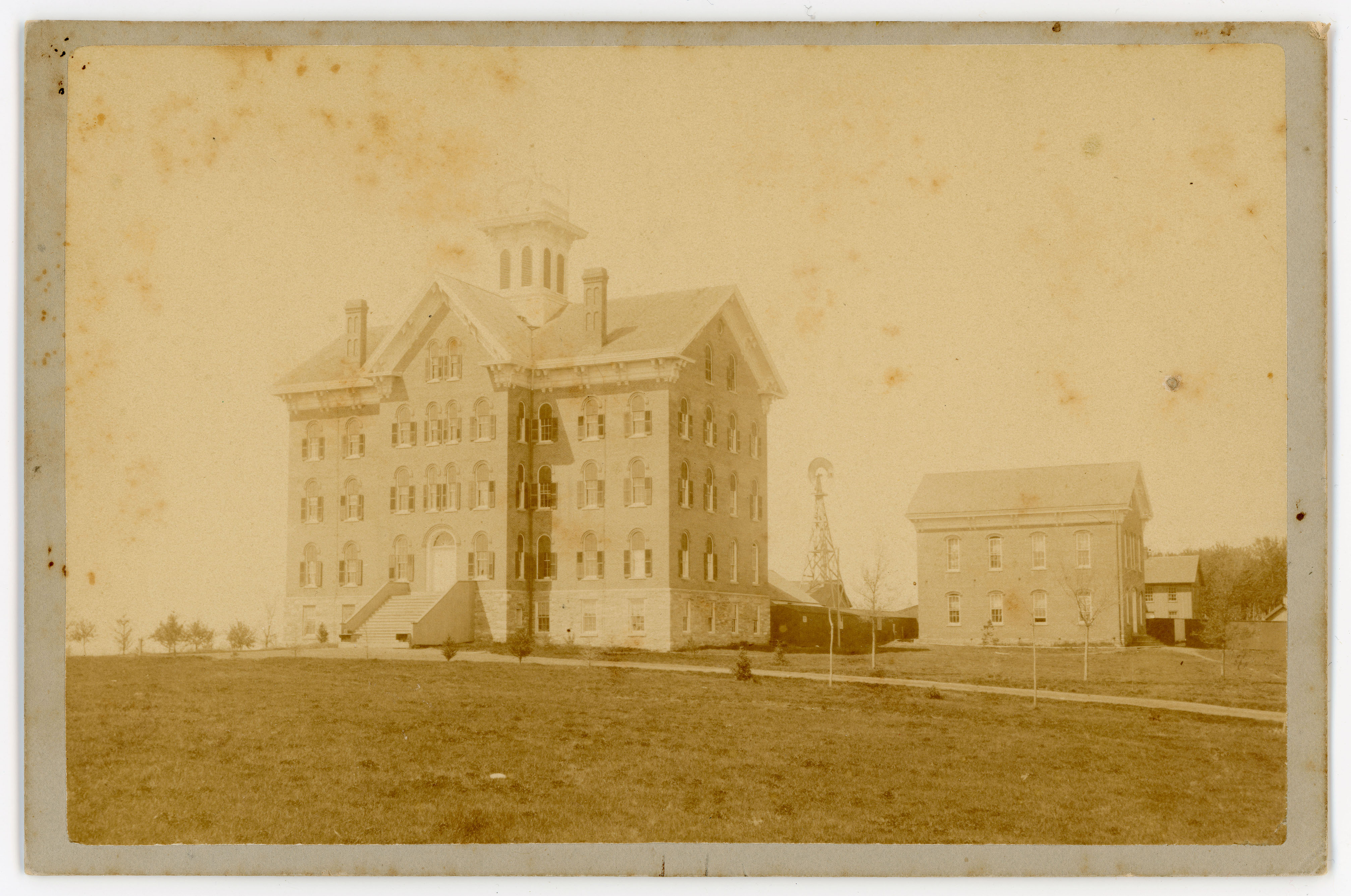 Building with cupola in foreground, windmill and smaller buildings in background