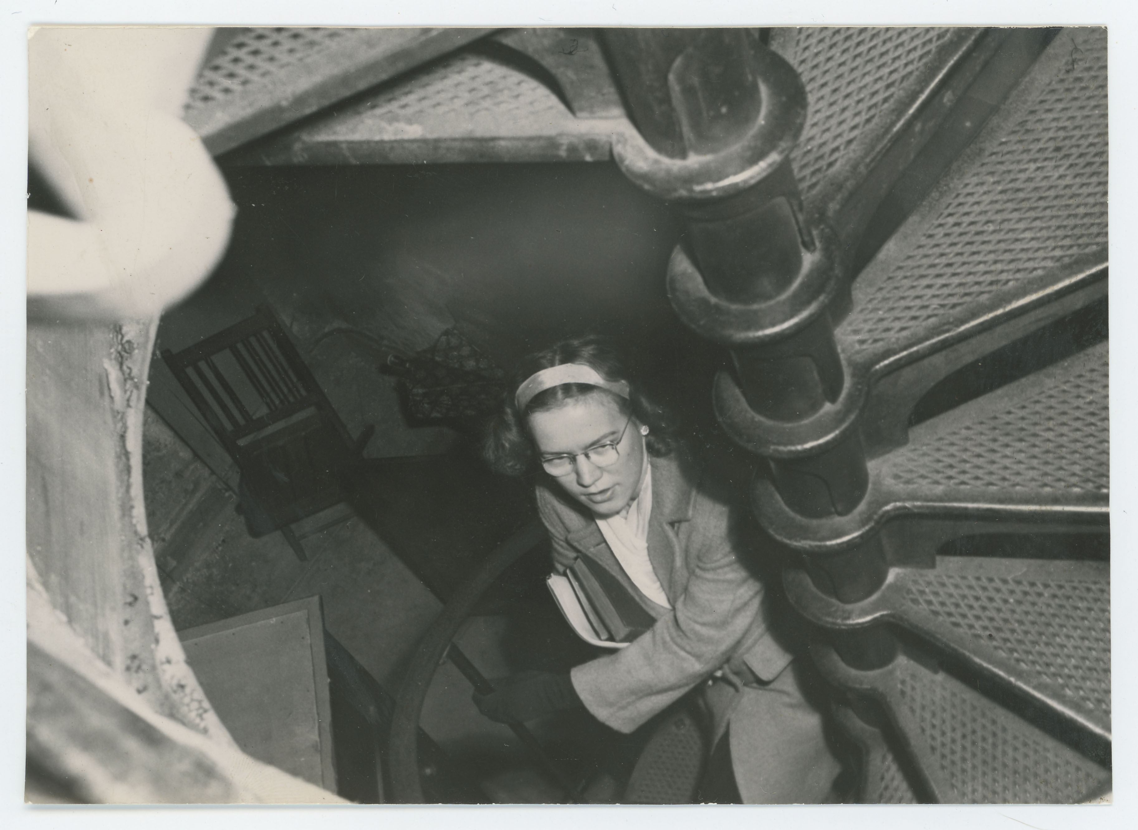 Woman climbing Campanile's spiral stairs carrying papers