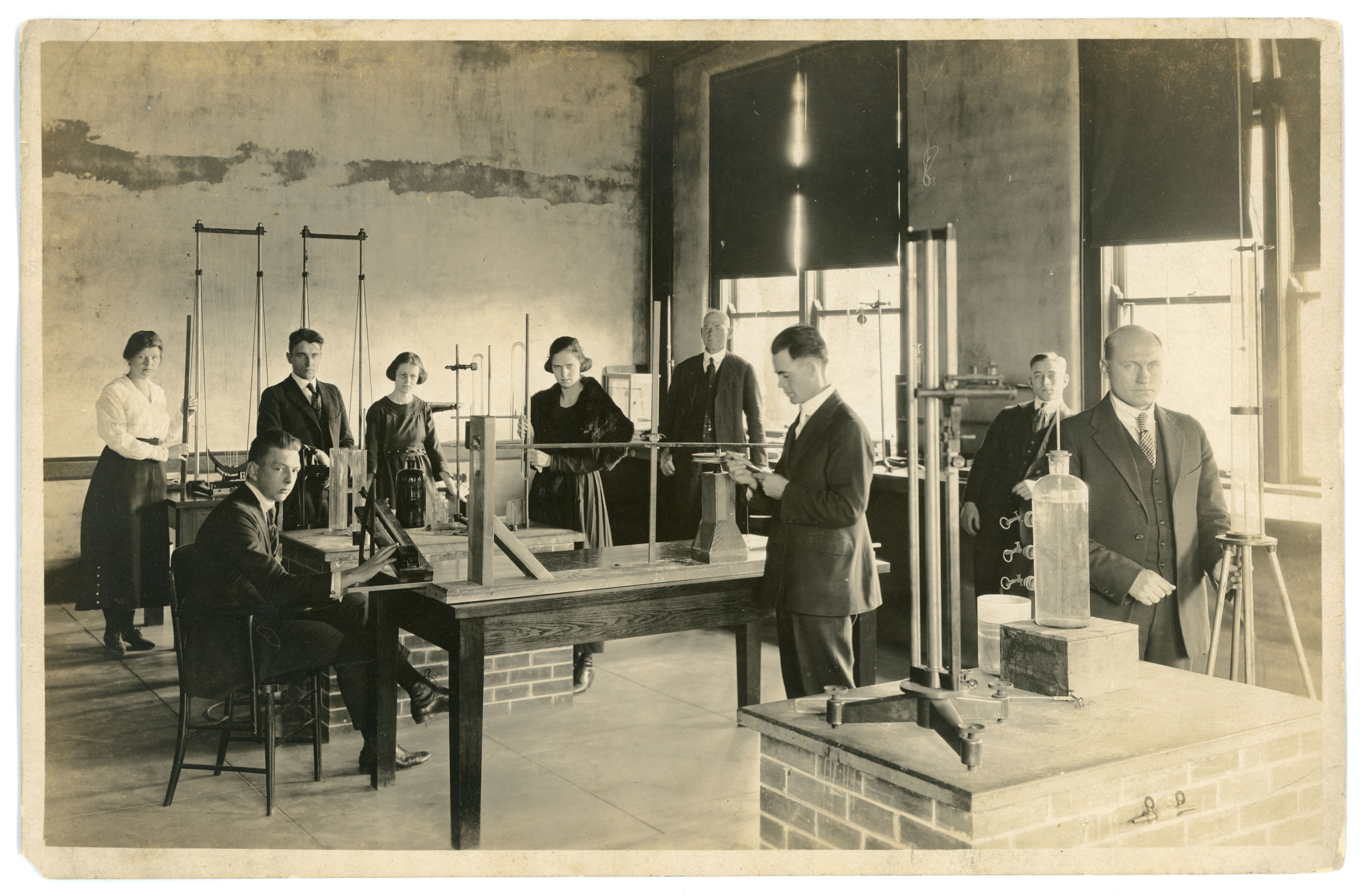 Three women and six men in room with early lab equipment