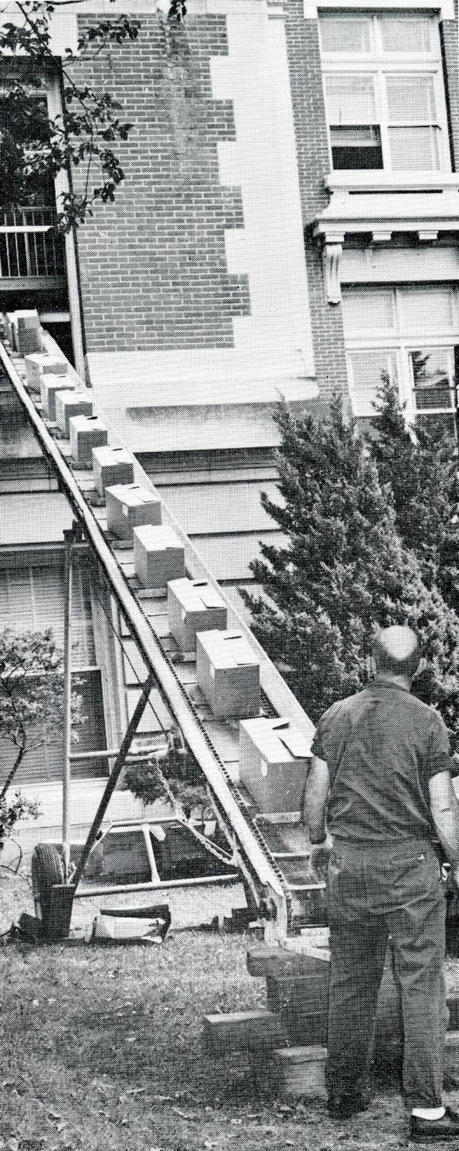 Conveyor belt elevator filled with boxes descending to ground from Seerley Hall window