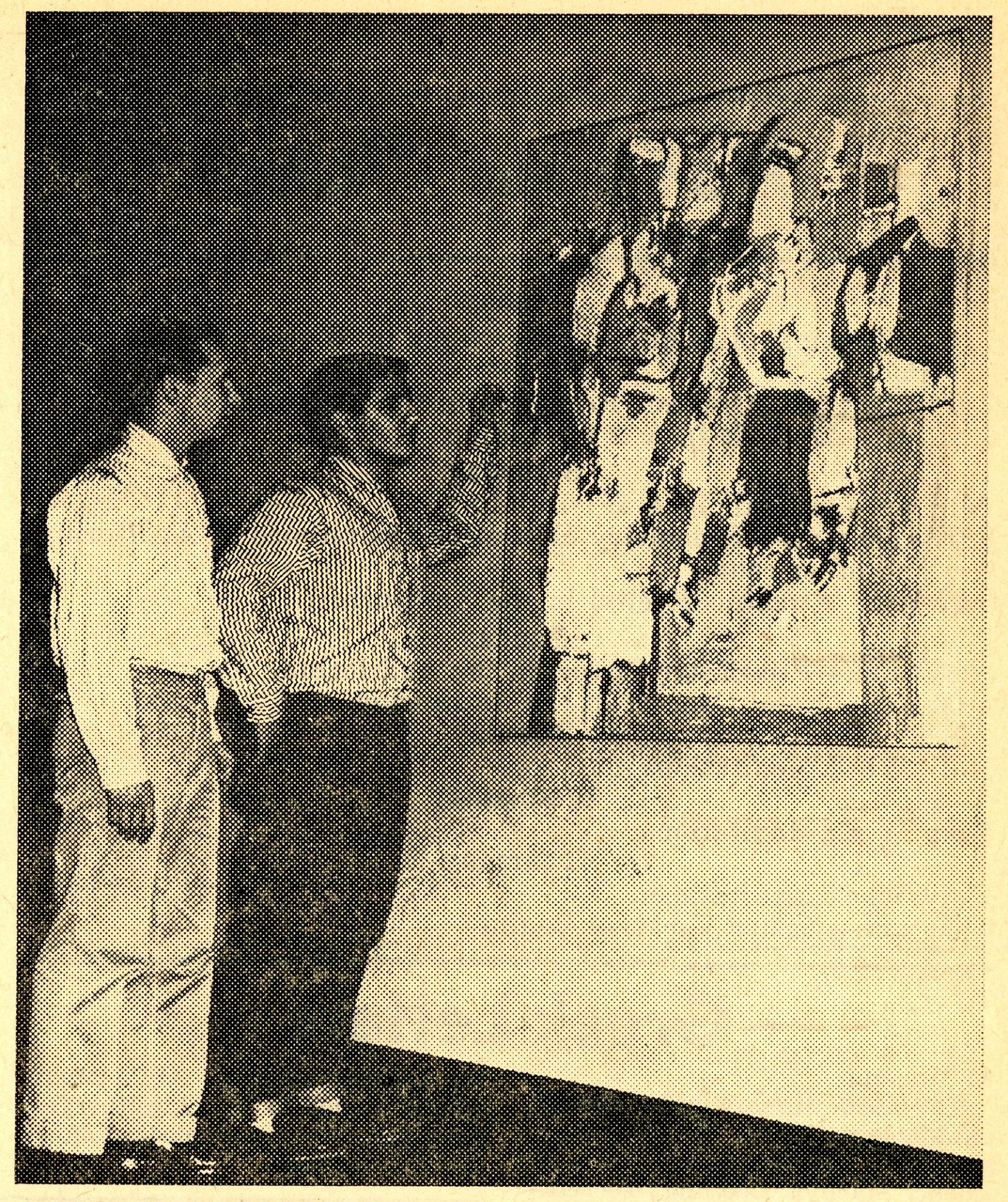 Two men observe abstract painting on wall