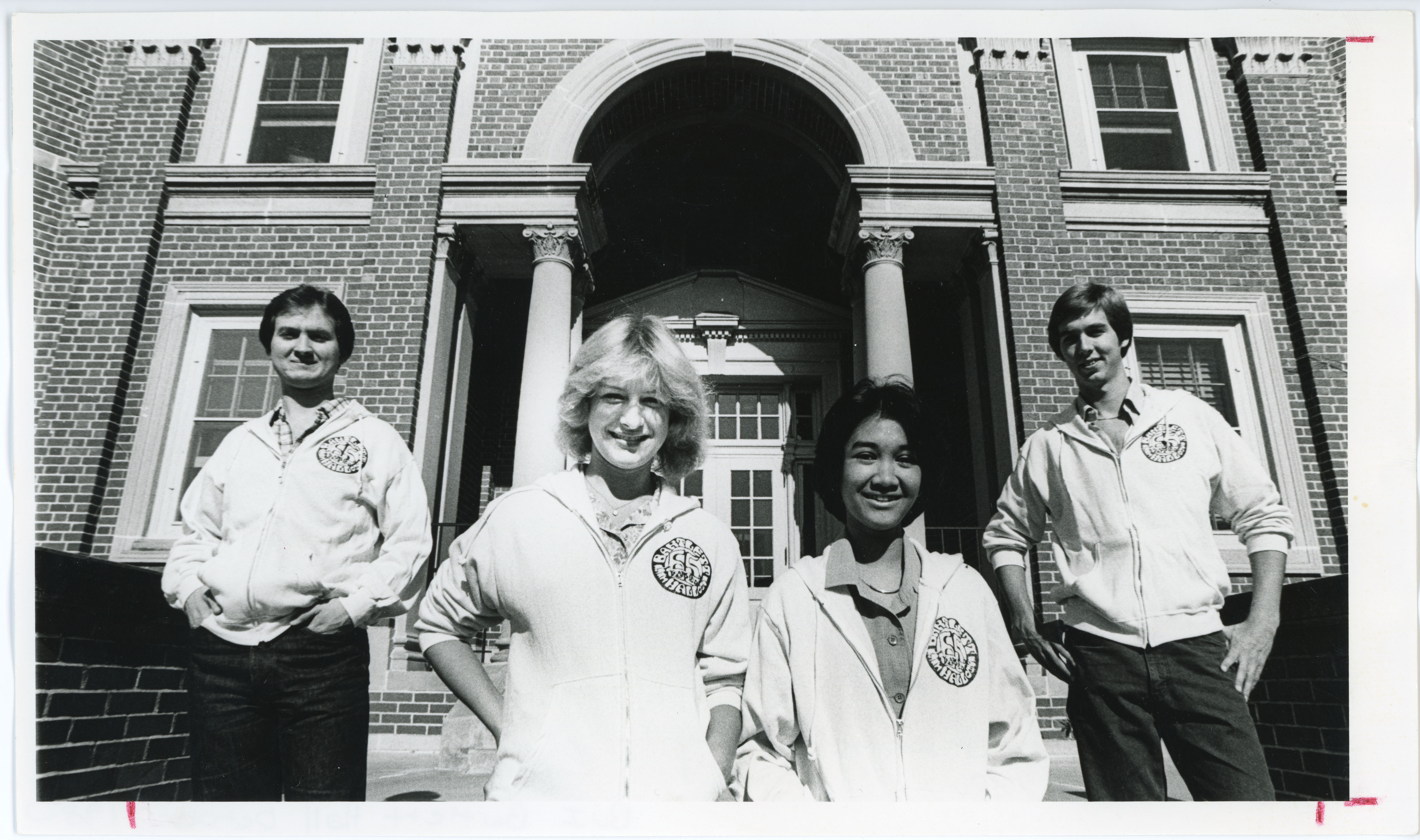 Four students standing outside Bartlett Hall, wearing Bartlett Hall 65th Anniversary shirts