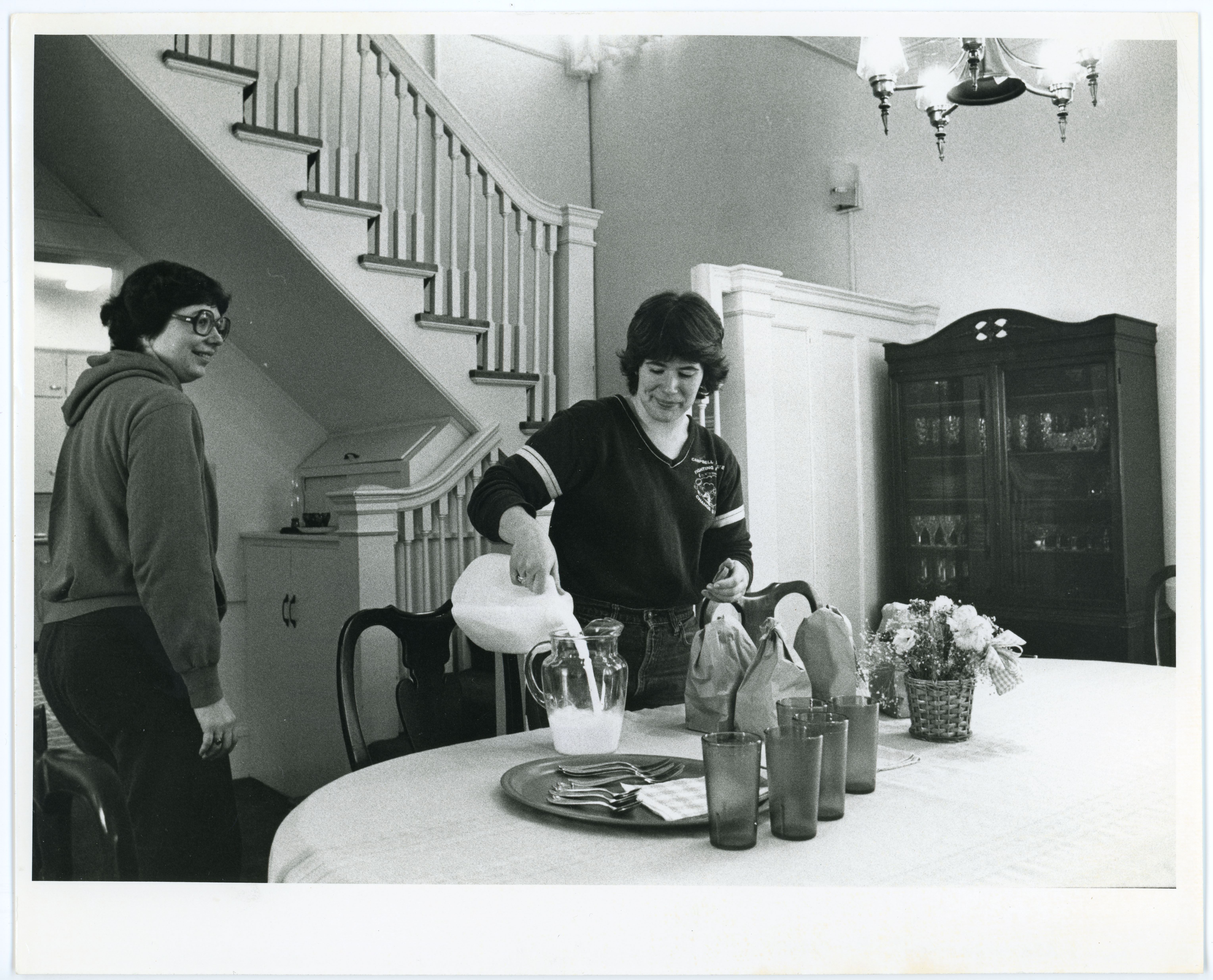 Two women pouring milk in home management house dining room