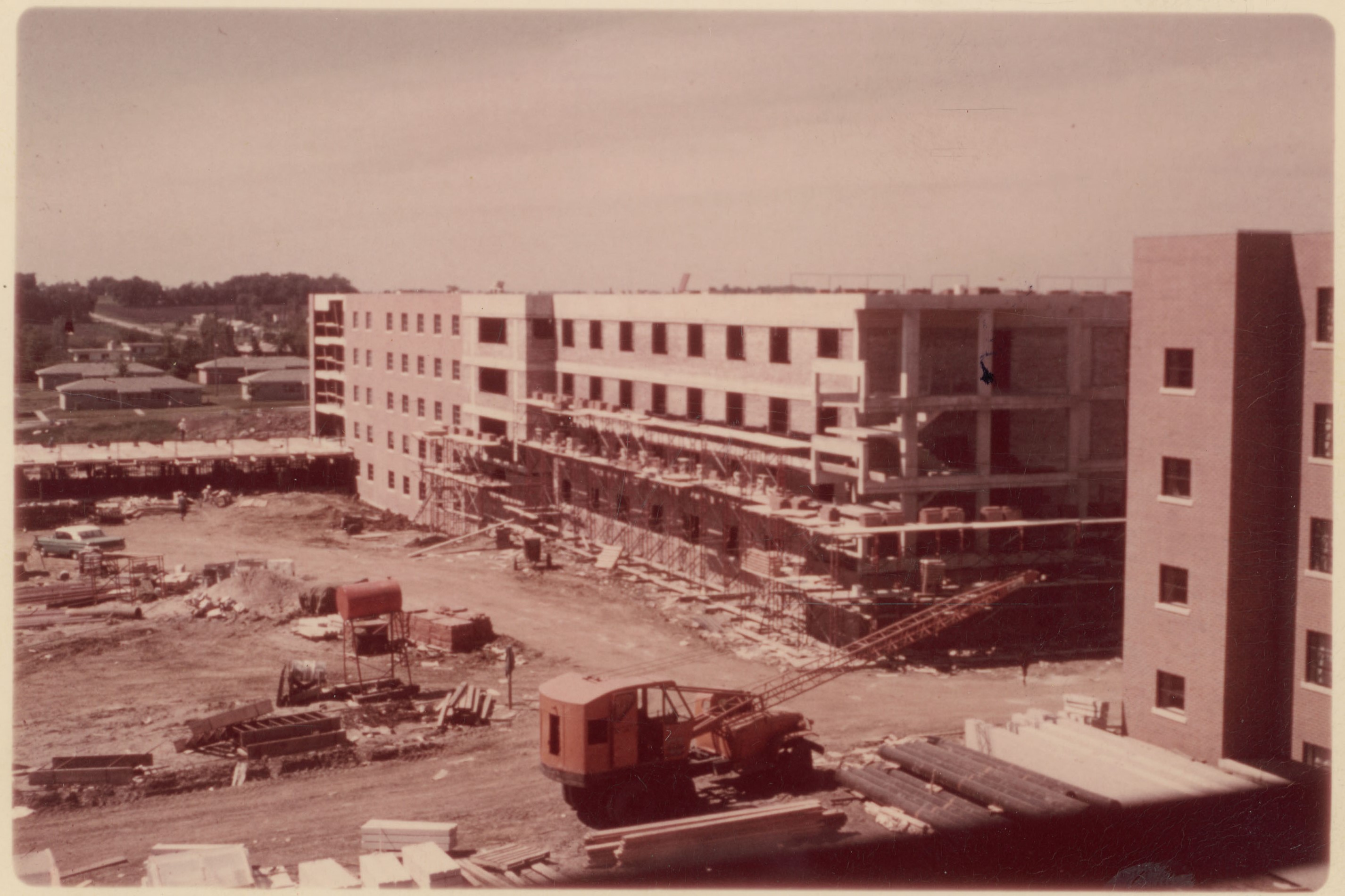 Partially-completed construction work on a building with equipment, supplies and scaffolding around it