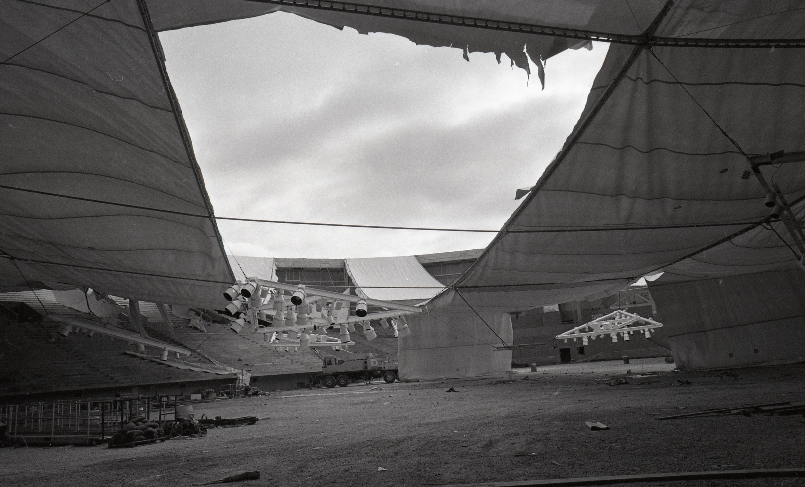 Shot from inside the stadium, a missing fabric roof panel reveals sky and other deflation storm damage to the roof