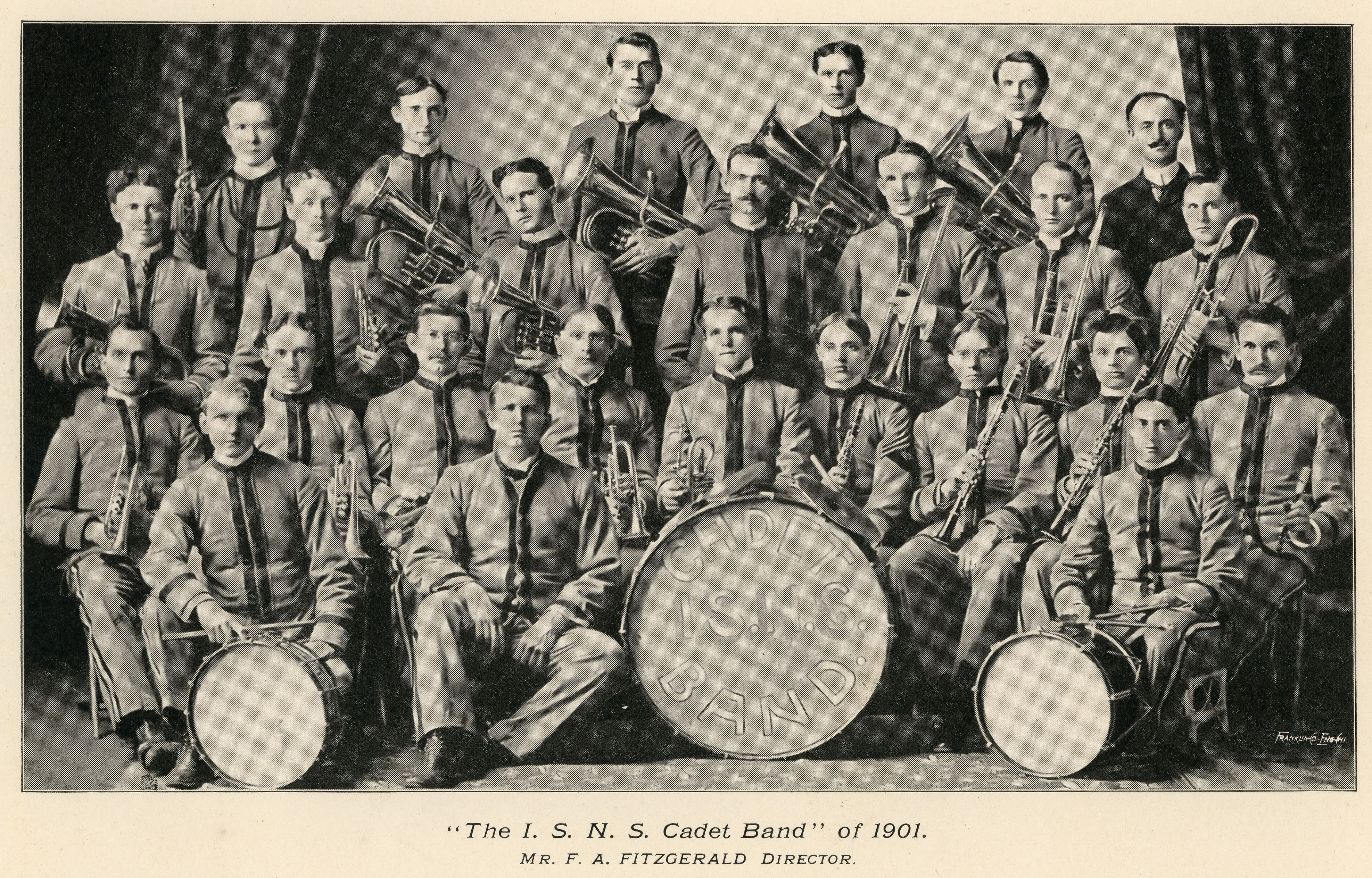 24 men in band uniforms holding instruments and their director posed for a photo, large base drum reads Cadet ISNS Band, caption reads The ISNS Cadet Band of 1901, Mr. F.A. Fitzgerald Director