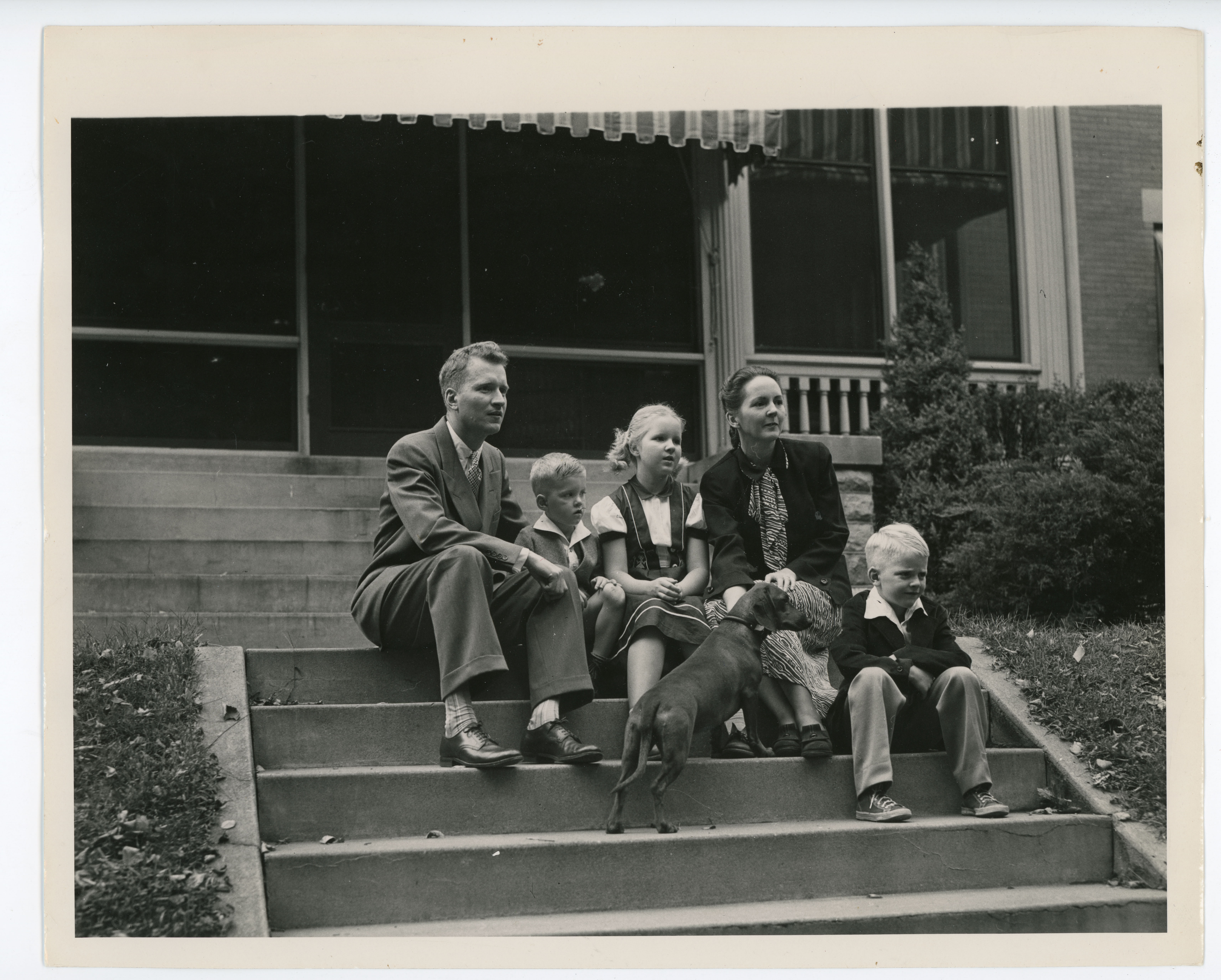 President Maucker with his family and their dog sitting on steps.