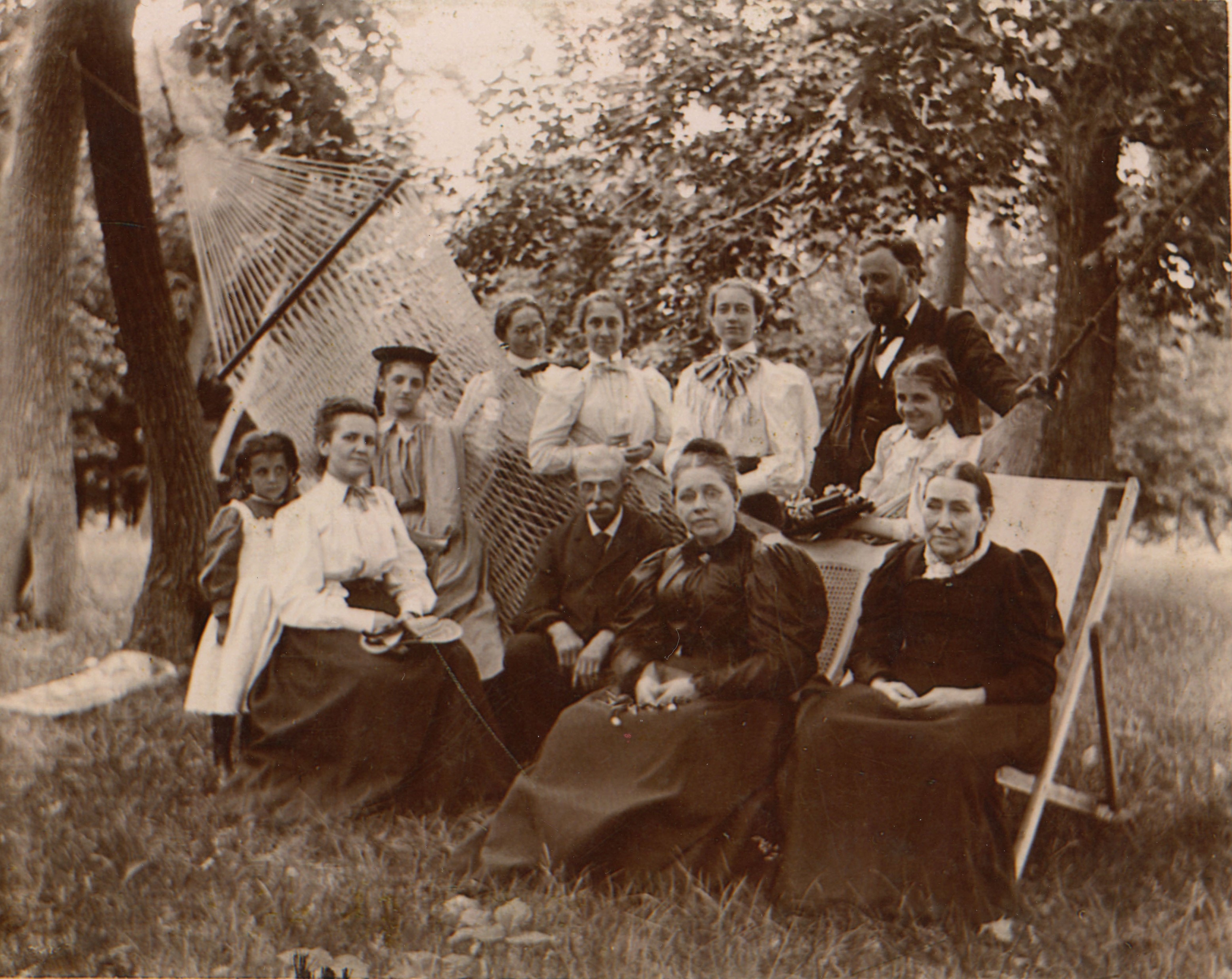 7 women, 2 men, and 2 girls seated and standing around a hammock