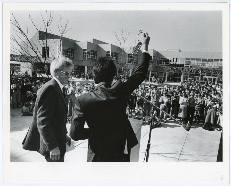 Photo of William Lew accepting the keys to the Kamerick Art Building from John Page in front of t large crowd 