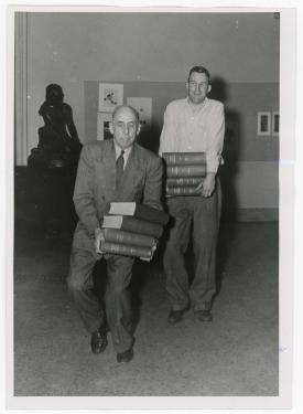 Professors E.J. Ritter (L) and R.J. Greef (R) carrying books during library book shift