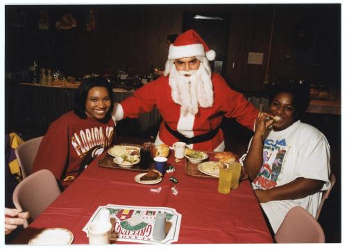 Two students posing with Santa at Christmas dinner