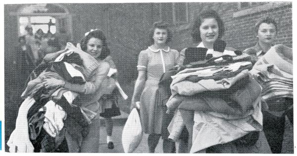 Several women moving piles of clothing and other items from Bartlett Hall to Lawther Hall