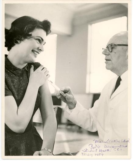 Photograph of Dr. French giving a student a polio vaccine