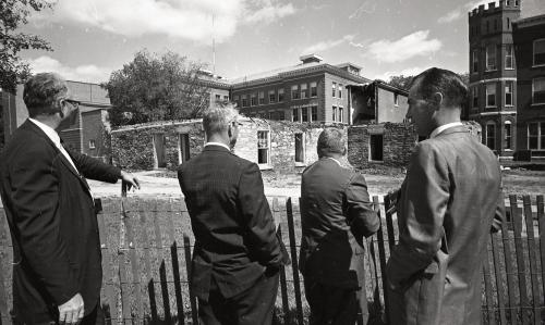 Photograph of four officials viewing the Central Hall ruins