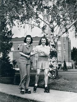 Photo of two women roller skating on campus