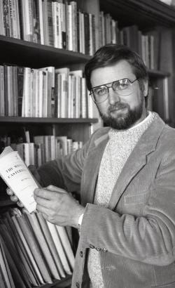 Photograph of Professor Scott Cawelti posing next to a bookshelf