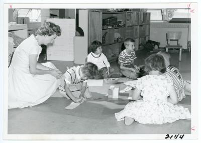 Teacher sits on the floor with young children