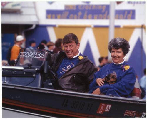 President Koob, his wife Yvonne, and their dog sitting in a boat during a parade