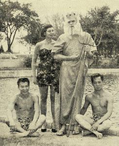 Four students pose in front of Prexy's Pond, they are dressed in costume as King Neptune, Queen Beth, and two attendants 