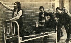 Photo of Towers residents participating in a bed race. Three individuals are on the bed while four others push.