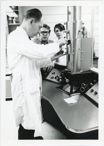 Warren Picklum working with a scientific instrument while two individuals watch
