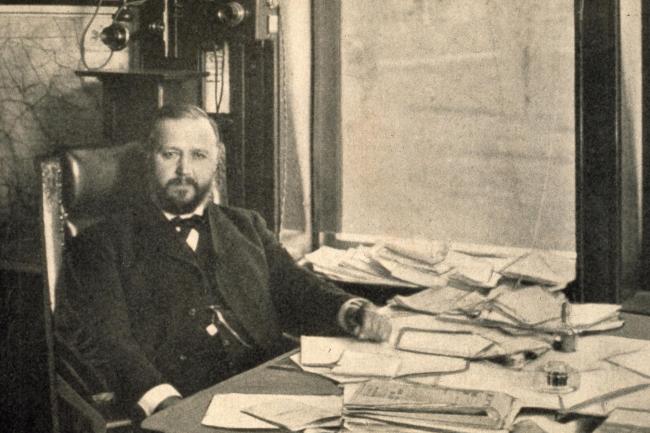 Photograph of President Homer H. Seerley sitting at a desk scattered with papers