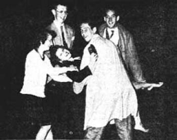 Four individuals carry a woman in a staged photo of the tradition of dunking freshmen in Prexy's Pond