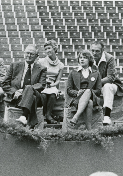 Four men and two women seated on a stage in the UNI-Dome with empty stadium seats behind them