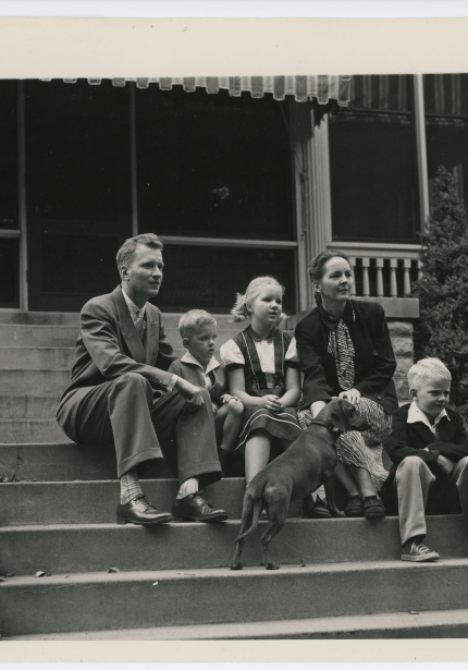 Maucker and his wife, children, and dog sitting on steps.