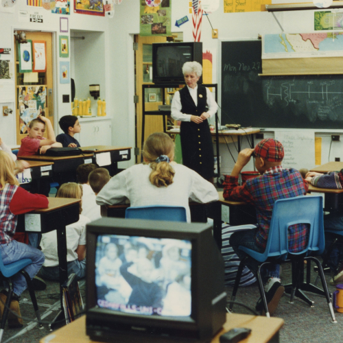 Instructor being filmed and broadcast teaching about twelve 5th graders in a classroom
