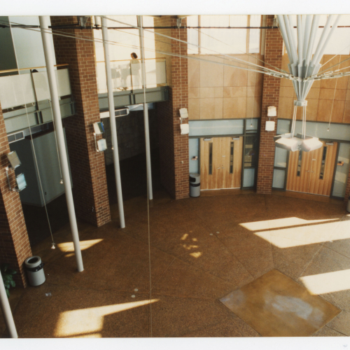 Two-level circular atrium of a building with many windows; a student is studying on the second level