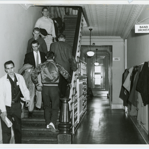 Approximately eight students on staircase to left, hallway down middle and coat hooks on right
