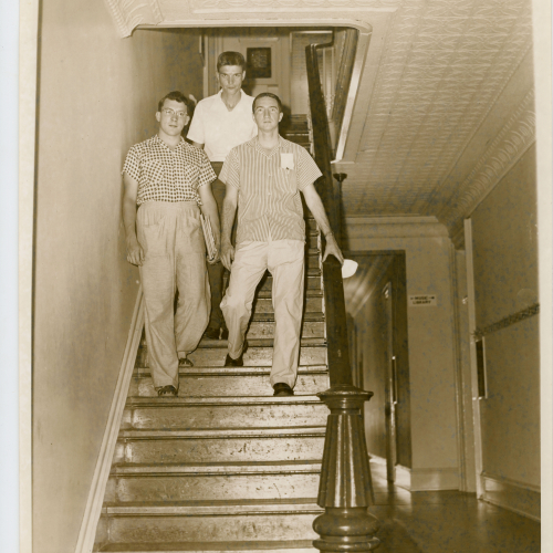 Three students descending staircase
