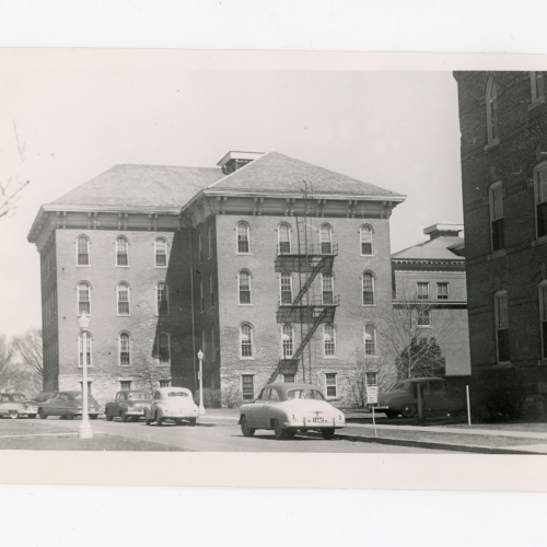 Brick building with fire escape and cars parked on street in front of it
