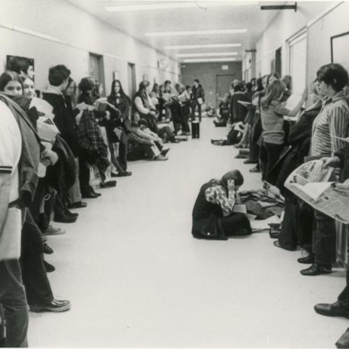 Students lining both sides of a long hallway inside a building