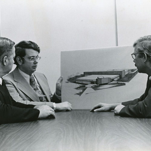 Three men looking at an architectural drawing of a building