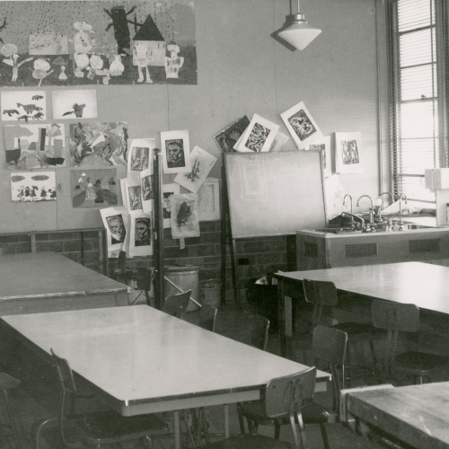 Classroom with tables and sink, art prints and posters hanging on back wall