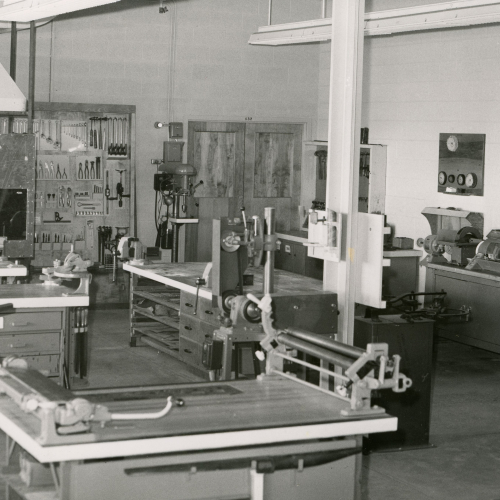 Classroom with mechanical equipment and workbenches, tools hanging on back wall