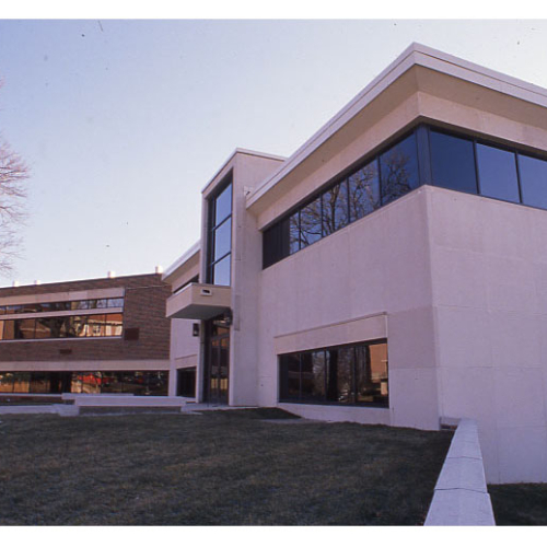Red brick and limestone building with many windows, sunlight reflecting from them