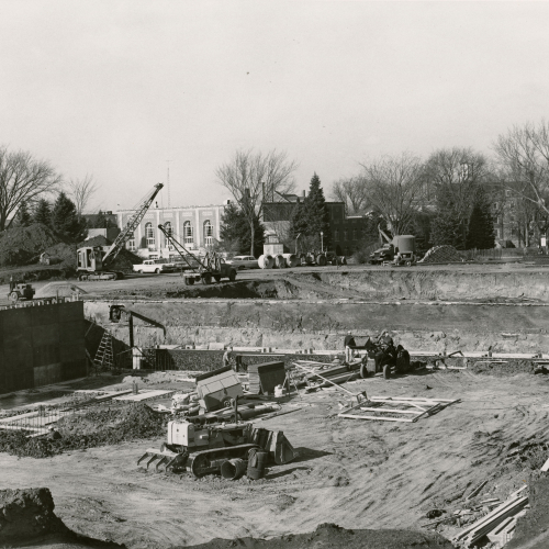 Construction equipment digging and leveling foundation for a building