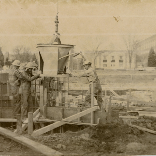 Construction workers supporting item lifted by crane