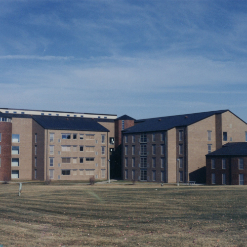 Brown and red four-to-five story brick building with two wings and a lower building of same material to the right
