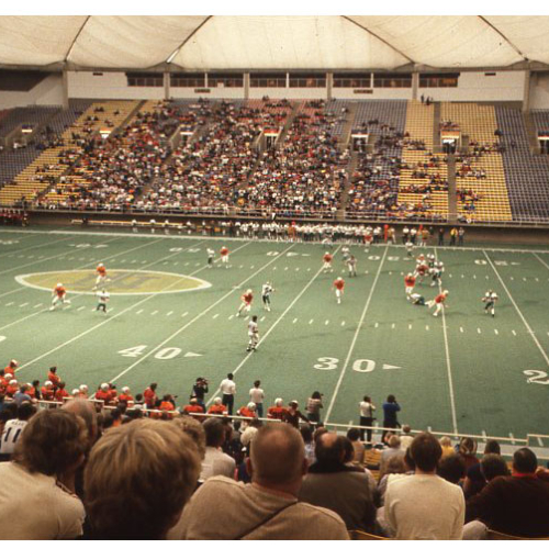 Indoor football game with players and on the field and crowd in the stands