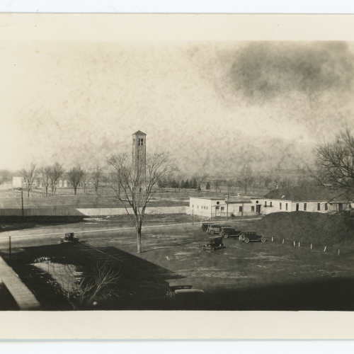 High shot of campus with views of early automobiles, buildings, Campanile and West Gym