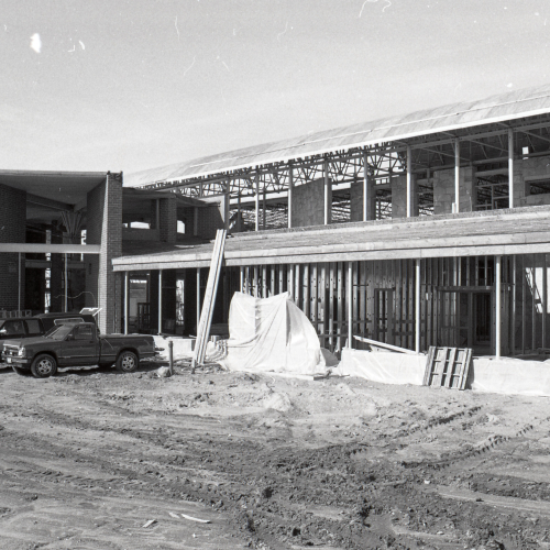 Two trucks parked in front of half of building during construction
