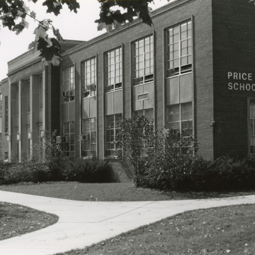 Side angle of two-story brick building with high windows, columned entrance, and lettering on side reading Price Laboratory School