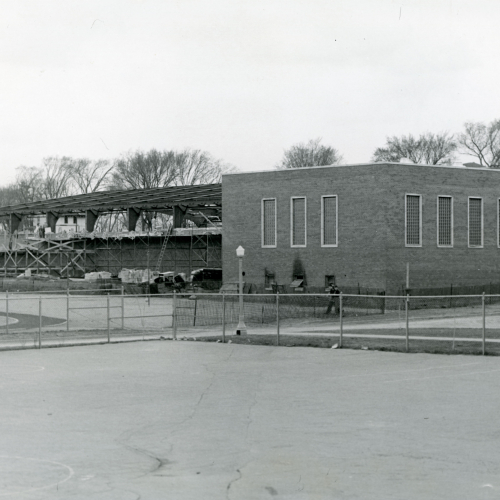 Brick building under construction; right section is bricked and has windows, left section is framed but not finished