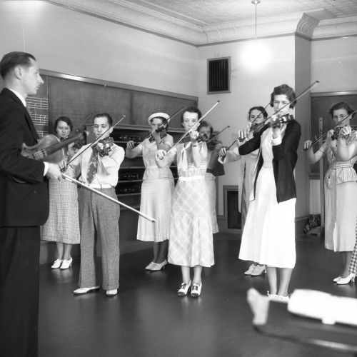 Professor teaching class of nine violin students